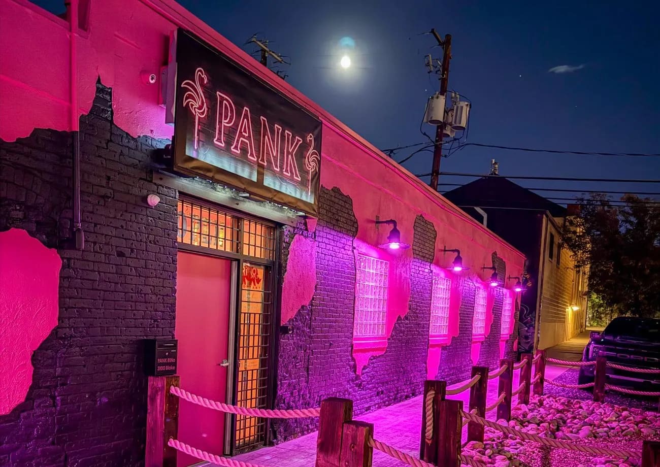 PANK at night: pink-washed brick, neon flamingo sign, rope fence